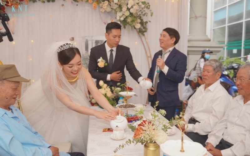 Khoảnh khắc cô dâu chú rể rót trà kính bề trên dưới sự hướng dẫn của chủ hôn