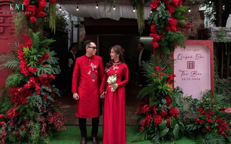 Cô dâu chú rể đứng trước cổng hoa Lễ Vu Quy tại nhà gái